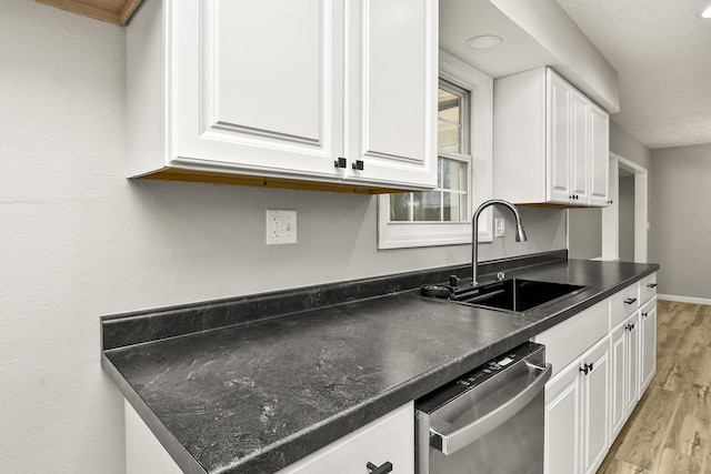 kitchen with sink, stainless steel dishwasher, white cabinets, and light wood-type flooring