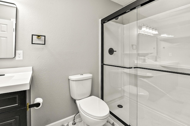 bathroom with vanity, a shower with door, and toilet