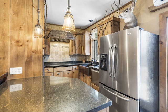 kitchen featuring decorative light fixtures, sink, dark stone countertops, decorative backsplash, and stainless steel refrigerator with ice dispenser