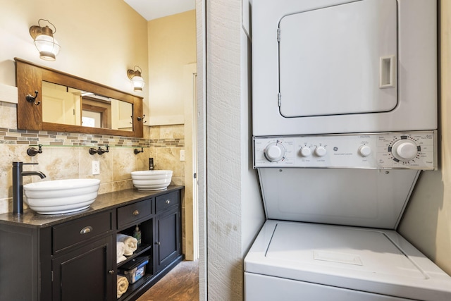 laundry room featuring stacked washer and clothes dryer, sink, and tile walls