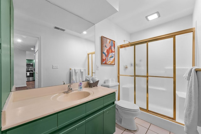 bathroom featuring a shower with door, vanity, tile patterned floors, and toilet