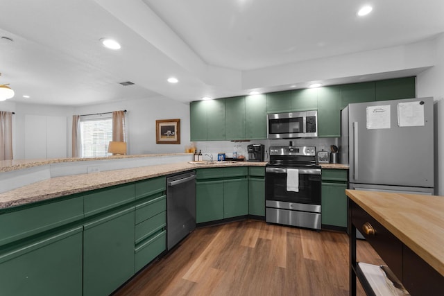 kitchen with stainless steel appliances, sink, green cabinets, and dark hardwood / wood-style flooring