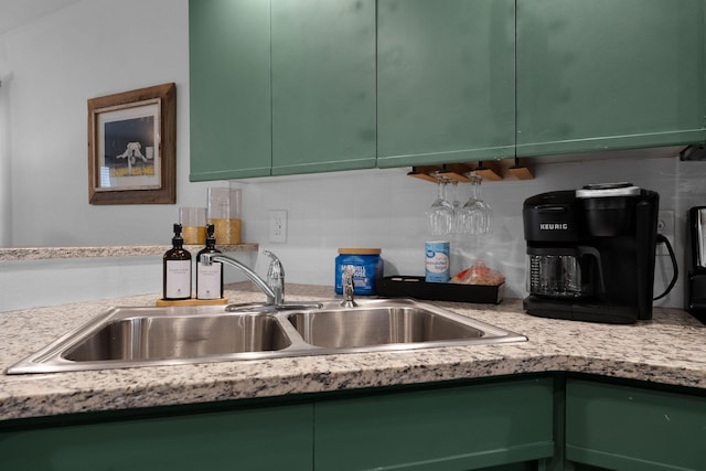 kitchen featuring sink, light stone counters, and green cabinetry