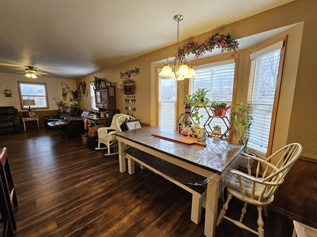 dining area featuring wood-type flooring, ceiling fan with notable chandelier, and a textured ceiling