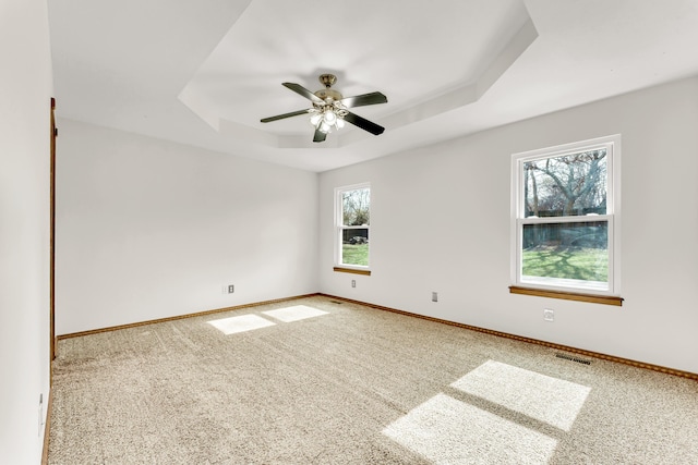 spare room with ceiling fan, a raised ceiling, and carpet floors