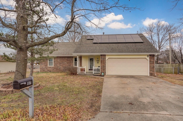 ranch-style house featuring a garage, a front lawn, and solar panels