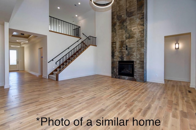 living room featuring a tiled fireplace, light hardwood / wood-style floors, and a high ceiling