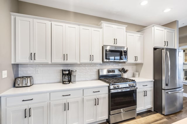 kitchen featuring white cabinetry, tasteful backsplash, stainless steel appliances, and light wood-type flooring