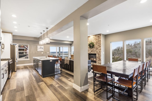 dining area featuring dark hardwood / wood-style flooring, sink, and a brick fireplace