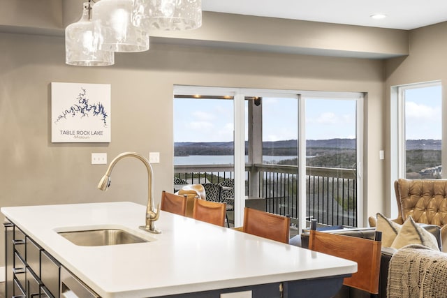 kitchen featuring hanging light fixtures, a water view, and sink