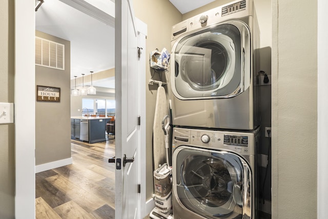 washroom with hardwood / wood-style flooring and stacked washer and clothes dryer