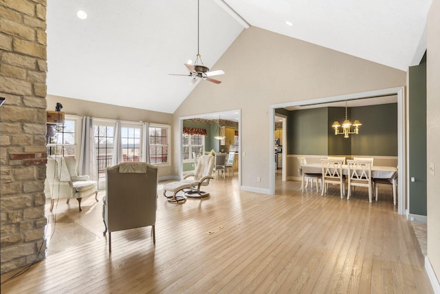 living room featuring ceiling fan with notable chandelier, high vaulted ceiling, and light hardwood / wood-style floors