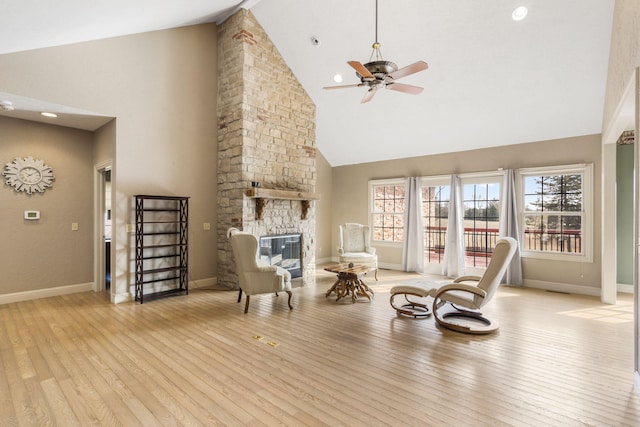 living area featuring a fireplace, high vaulted ceiling, ceiling fan, and light wood-type flooring