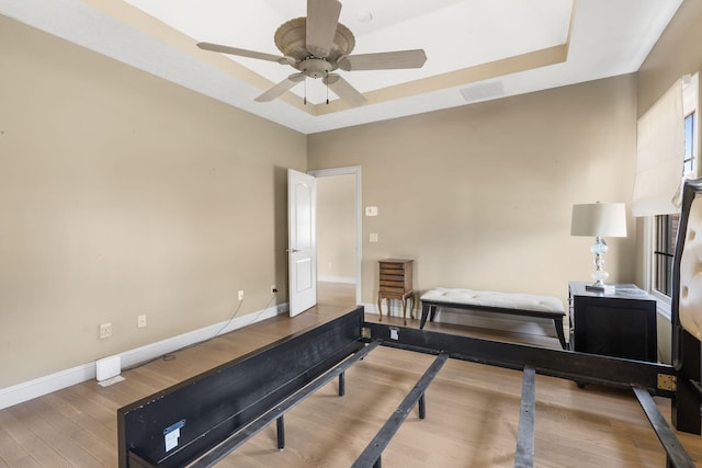 workout room featuring ceiling fan, a raised ceiling, and hardwood / wood-style floors