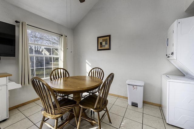 dining area featuring stacked washer and dryer, light tile patterned floors, vaulted ceiling, and ceiling fan