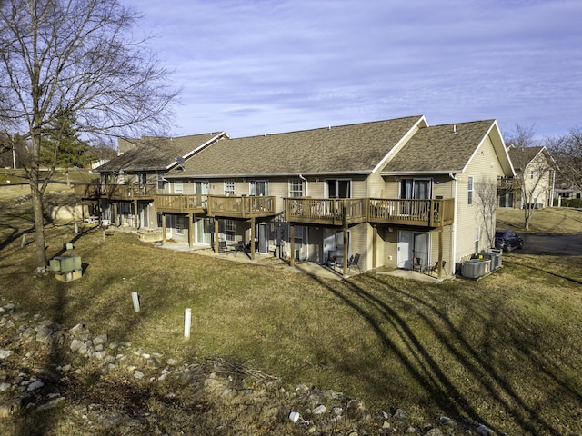 back of property featuring a wooden deck, a lawn, and a patio