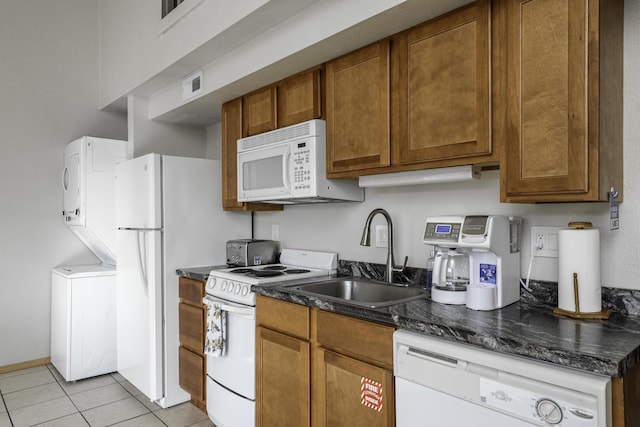 kitchen featuring stacked washer / drying machine, sink, light tile patterned floors, and white appliances