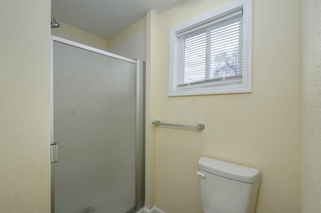 bathroom featuring toilet and a shower with shower door