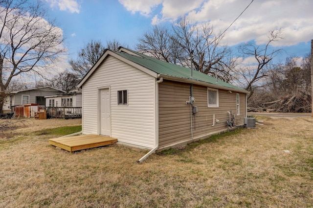 view of side of property with a wooden deck, central AC unit, and a lawn