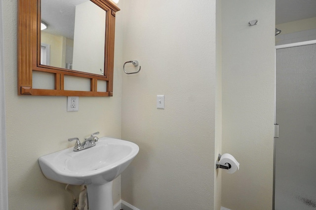 bathroom featuring a shower with shower door and sink