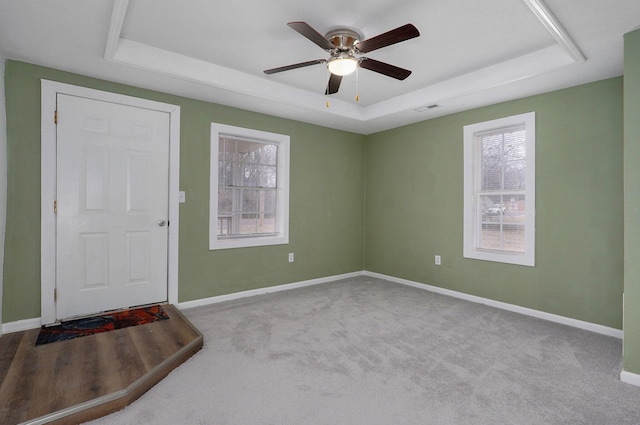 carpeted empty room featuring a raised ceiling and ceiling fan