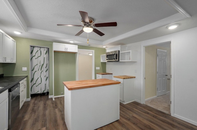 kitchen with butcher block countertops, appliances with stainless steel finishes, white cabinetry, a kitchen island, and a raised ceiling