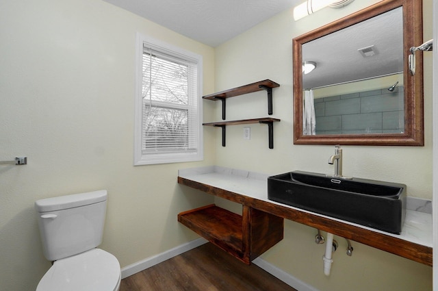 bathroom featuring hardwood / wood-style flooring, walk in shower, sink, and toilet