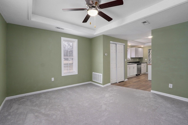 carpeted empty room featuring ceiling fan and a tray ceiling