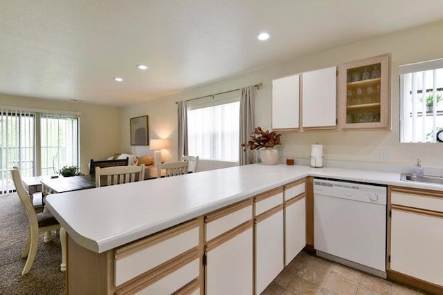 kitchen with plenty of natural light, white cabinets, white dishwasher, and kitchen peninsula