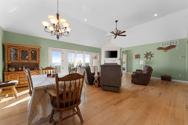 dining area with lofted ceiling, ceiling fan with notable chandelier, and light wood-type flooring