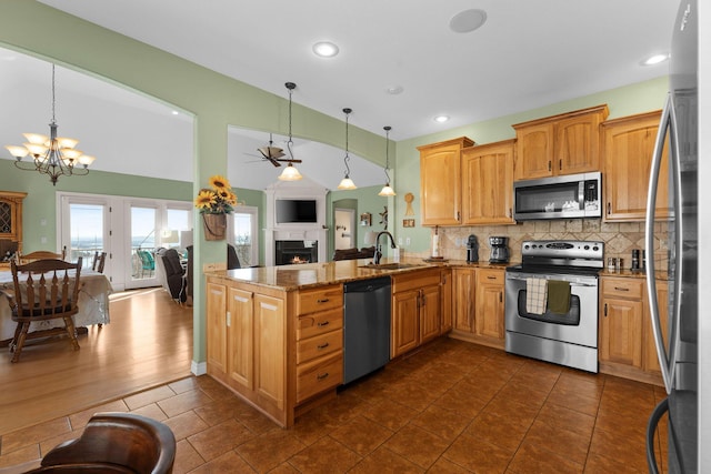 kitchen featuring stainless steel appliances, sink, pendant lighting, and stone counters