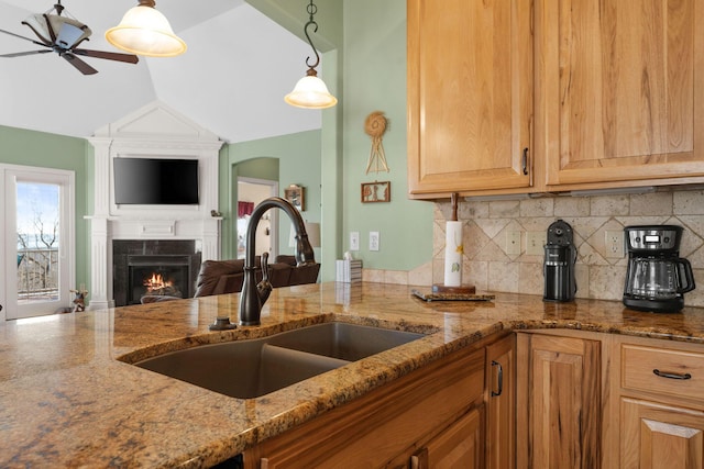 kitchen featuring stone countertops, sink, decorative backsplash, hanging light fixtures, and ceiling fan