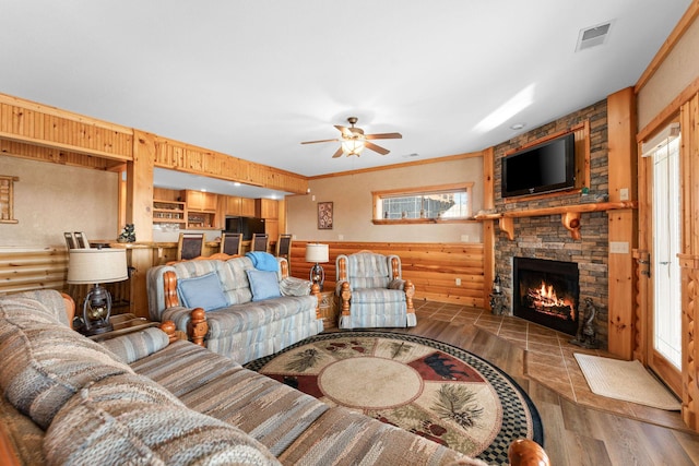 living room with hardwood / wood-style flooring, ceiling fan, a fireplace, and wood walls