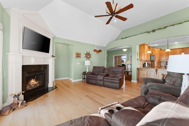 living room with ceiling fan, lofted ceiling, a fireplace, and light hardwood / wood-style floors