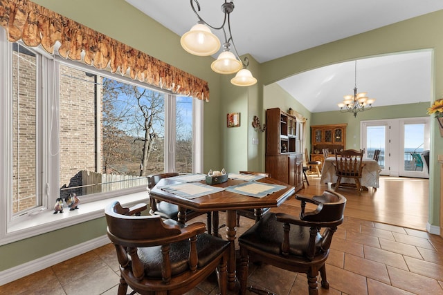 dining area featuring an inviting chandelier, a wealth of natural light, light tile patterned flooring, and vaulted ceiling