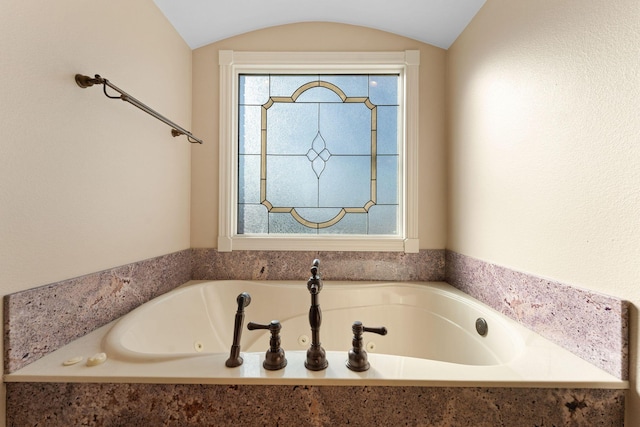 bathroom with lofted ceiling and tiled tub