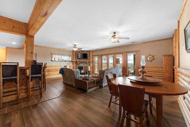 dining room with ceiling fan, dark wood-type flooring, crown molding, and a fireplace