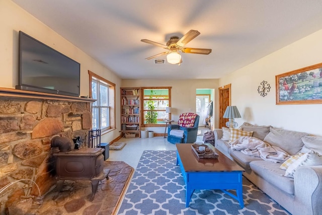 living room with ceiling fan and a wood stove