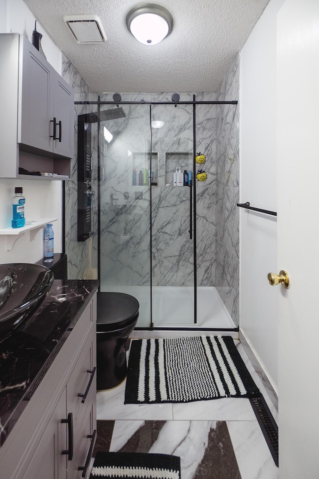 bathroom featuring vanity, an enclosed shower, a textured ceiling, and toilet