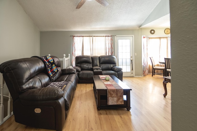 living room featuring ceiling fan, vaulted ceiling, light hardwood / wood-style flooring, and a textured ceiling