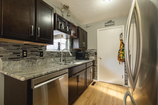 kitchen featuring stainless steel appliances, light stone countertops, sink, and light hardwood / wood-style flooring