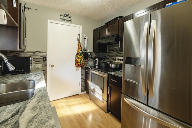 kitchen with sink, light hardwood / wood-style flooring, appliances with stainless steel finishes, light stone countertops, and decorative backsplash