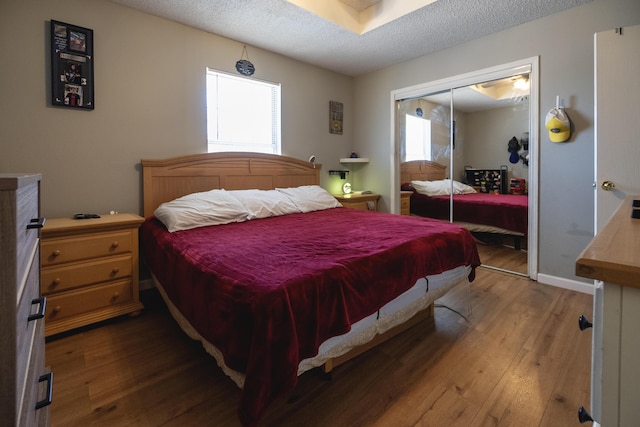 bedroom featuring multiple windows, hardwood / wood-style flooring, a closet, and a textured ceiling