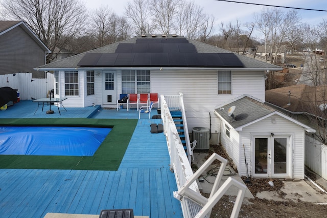 back of property featuring solar panels, a swimming pool side deck, an outdoor structure, central AC unit, and french doors