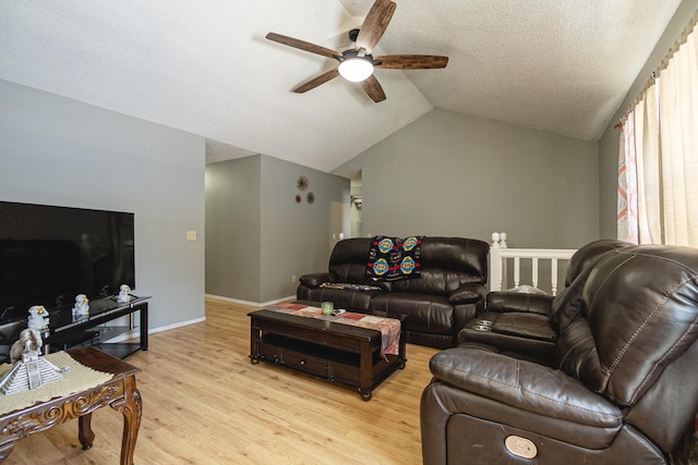 living room featuring ceiling fan, vaulted ceiling, light hardwood / wood-style flooring, and a textured ceiling