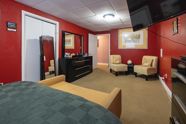 carpeted bedroom featuring a closet and a drop ceiling