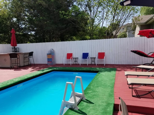 view of swimming pool with exterior bar and a deck