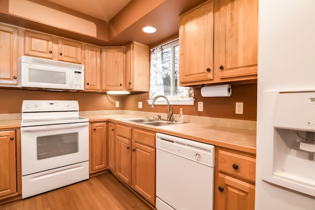 kitchen with sink, white appliances, light brown cabinets, and light wood-type flooring