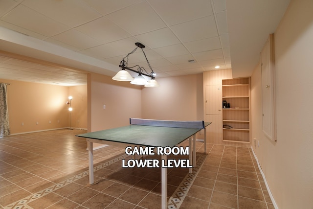 rec room with dark tile patterned floors and a drop ceiling