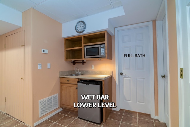 kitchen featuring dark tile patterned floors, sink, stainless steel microwave, and dishwashing machine